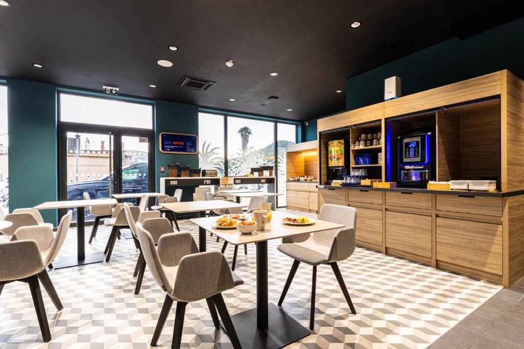 a dining room with tables and chairs in a restaurant at Holiday Inn Express Ajaccio by IHG in Ajaccio