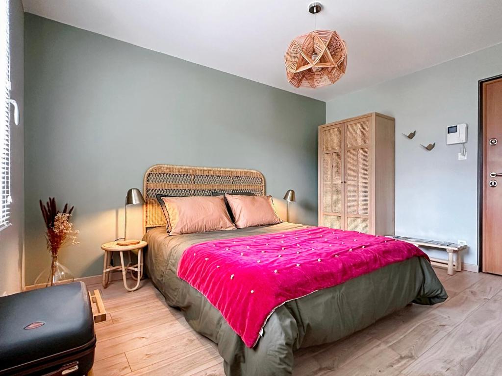 a bedroom with a large bed with a pink blanket at Charmant studio avec parking in Eguisheim