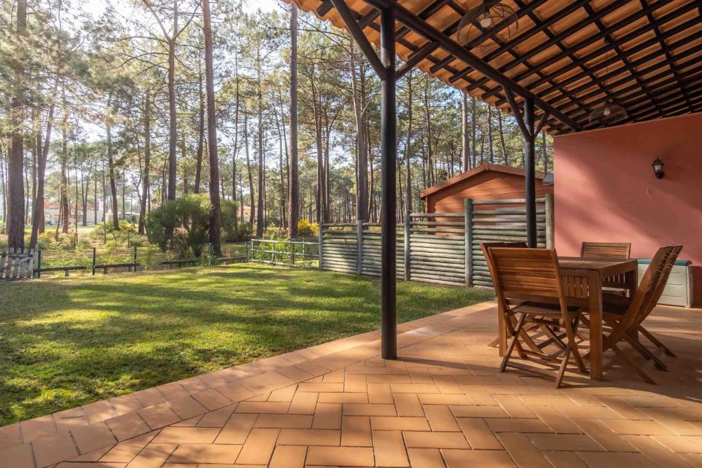 eine Terrasse mit einem Tisch und Stühlen sowie einem Hof in der Unterkunft Sun e Sea Golf House in Aroeira