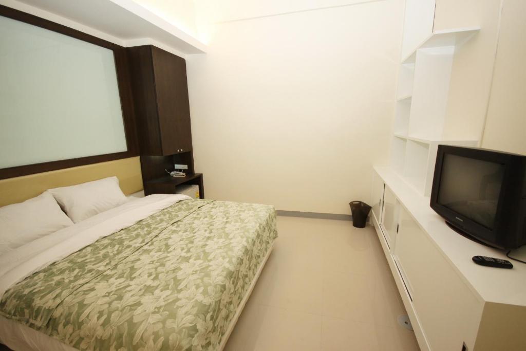 a bedroom with a bed and a flat screen tv at Nine Place Sukhumvit 40 in Bangkok