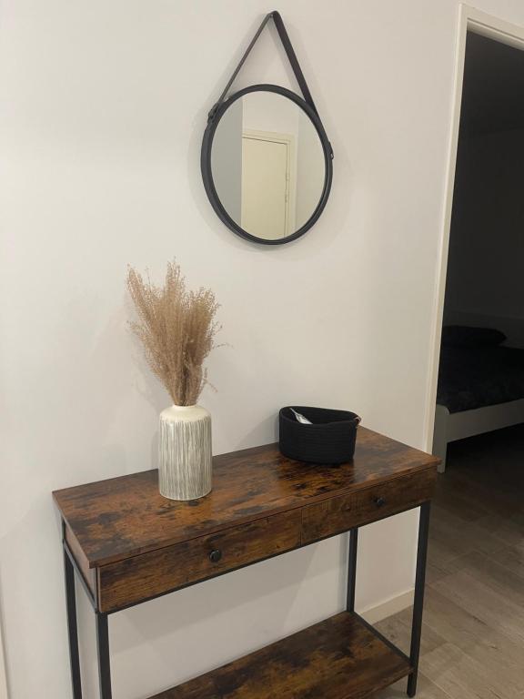 une table en bois avec un miroir sur un mur dans l'établissement Appartement cosy proche Paris, à Bezons
