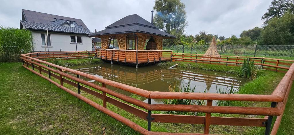 uma cerca de madeira em torno de um lago com um gazebo em Zacisze na Roztoczu em Horyniec