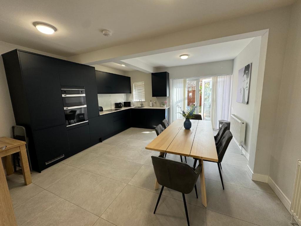 a kitchen and dining room with a wooden table and chairs at Charming 4 Bed House, 20 Minutes to Central London in Edgware