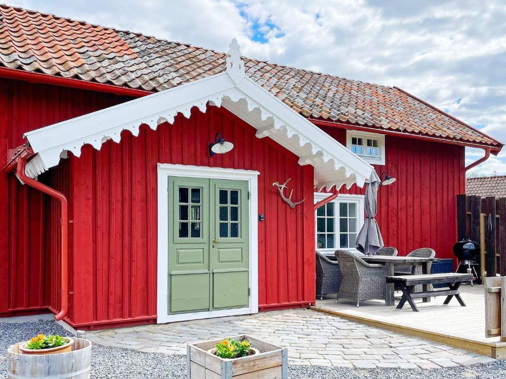 een rode schuur met een groene deur op een patio bij Holiday home Mellösa IV in Mellösa