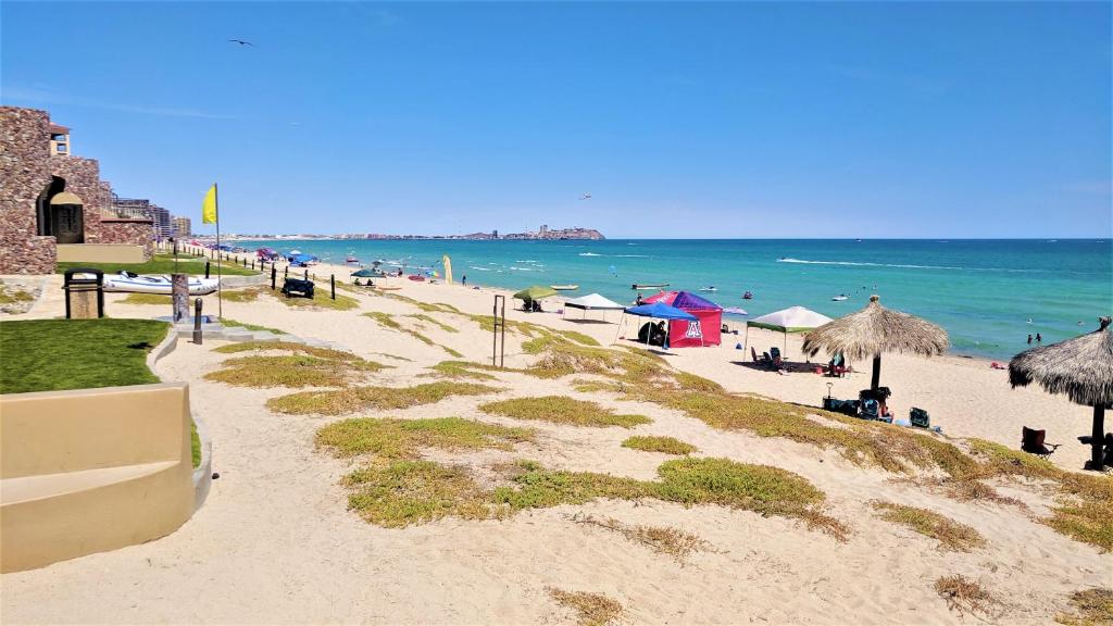 a beach with people and umbrellas and the ocean at Bella Sirena Luxury Resort 205-D in Puerto Peñasco