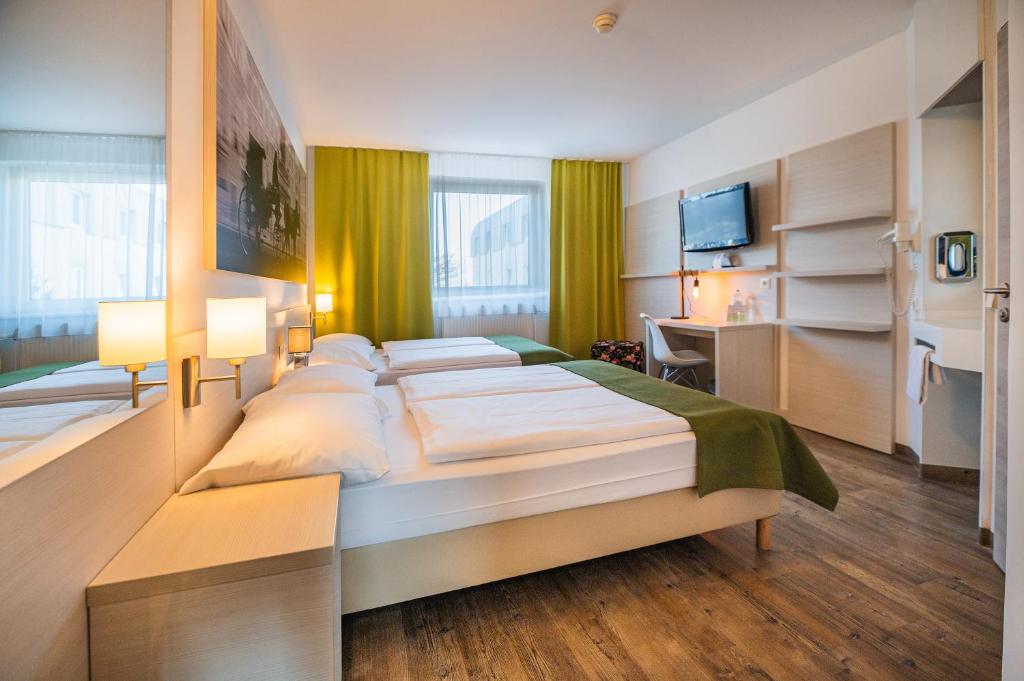 a hotel room with two beds and a desk at LifeHotel Vienna Airport in Fischamend Dorf