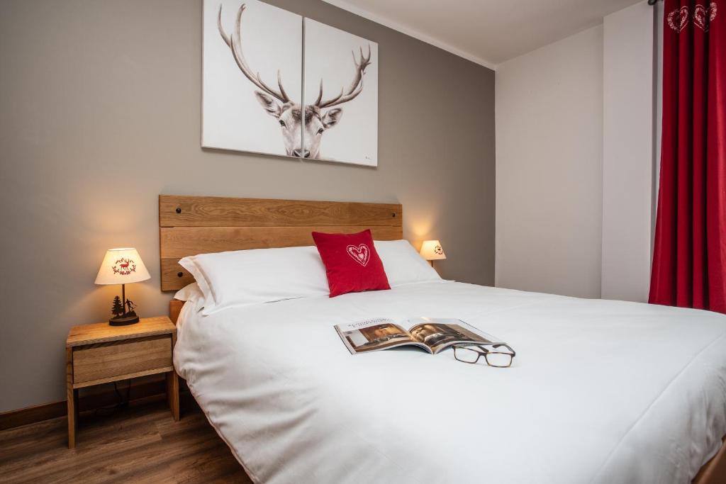 a bedroom with a white bed with a deer head on it at Apartments Les Crouses in Valtournenche