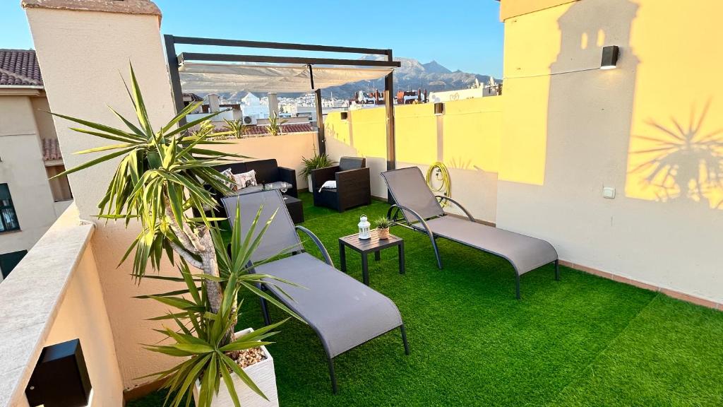 een balkon met stoelen en een tafel en gras bij Ático Calas de Nerja in Nerja