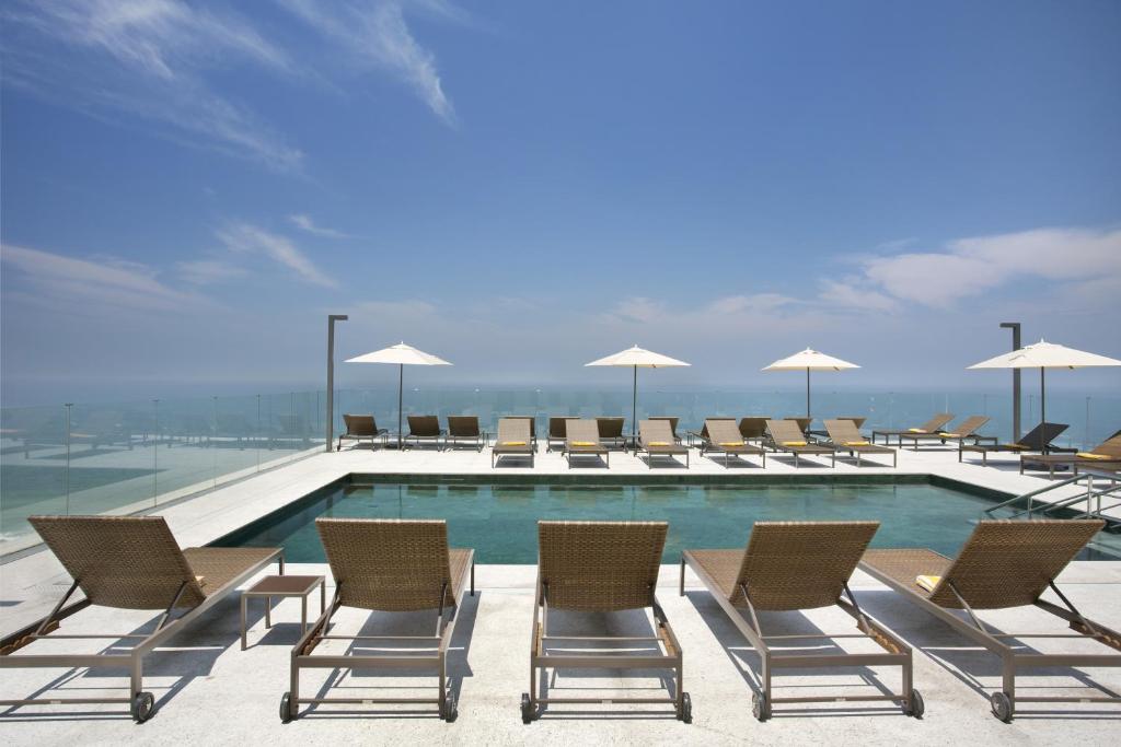 a pool with chairs and umbrellas on a building at Windsor Marapendi Hotel in Rio de Janeiro