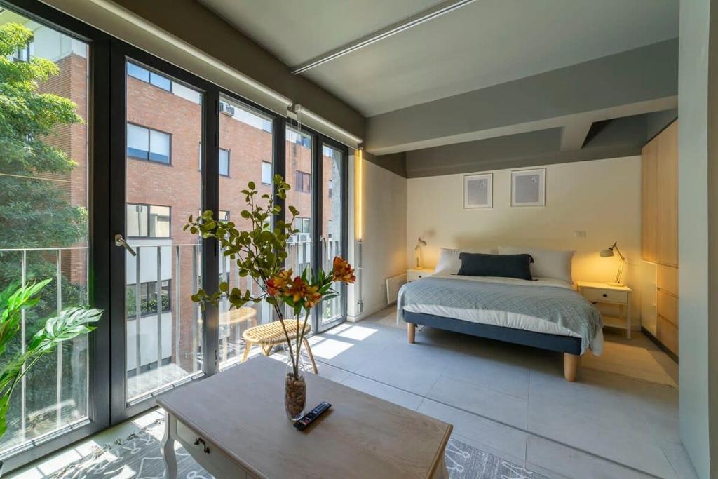 a bedroom with a bed and large windows at Encantador espacio cercano de Barrio Italia in Santiago