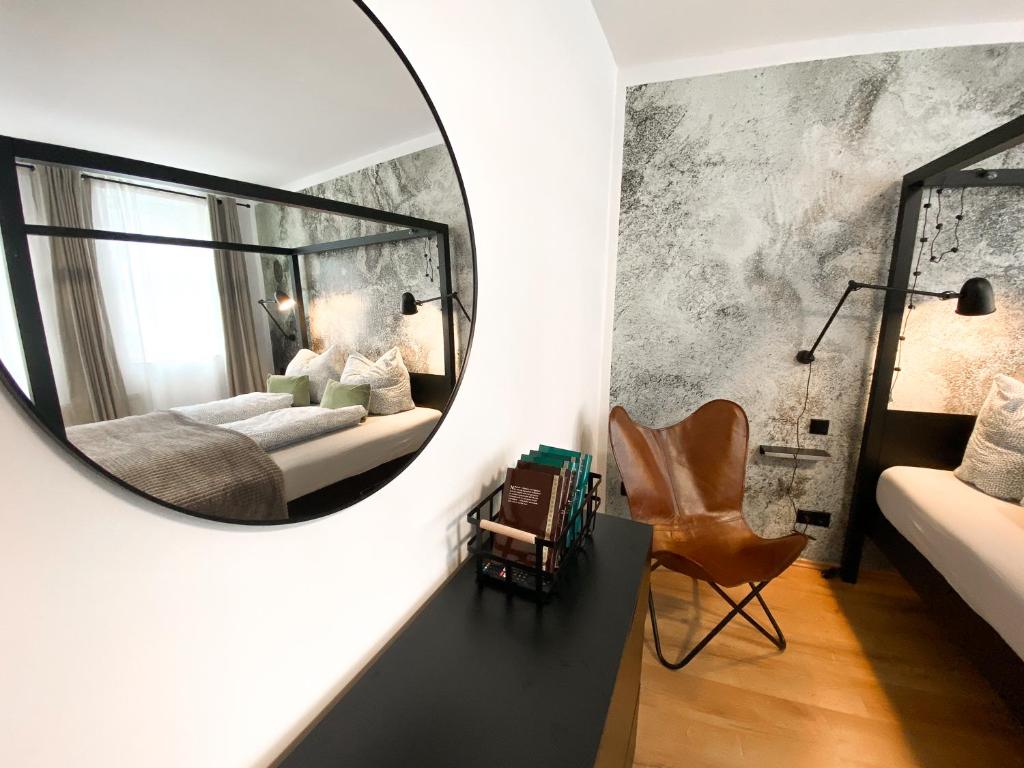 a mirror in a bedroom with a bed and a chair at WEINQUARTIER Weingarten Loft 70 qm 2 SZ Altstadt Balkon Himmelbett Küche Parkplatz in Naumburg