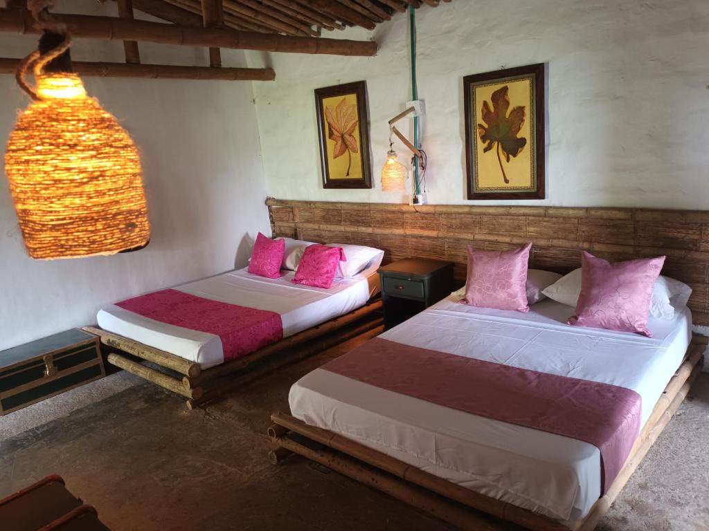 two beds in a room with pink pillows at Posadas rurales arabi in Pereira