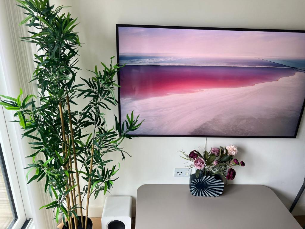 a flat screen tv hanging on a wall with plants at Impeccable 1-Bed Apartment in Barking