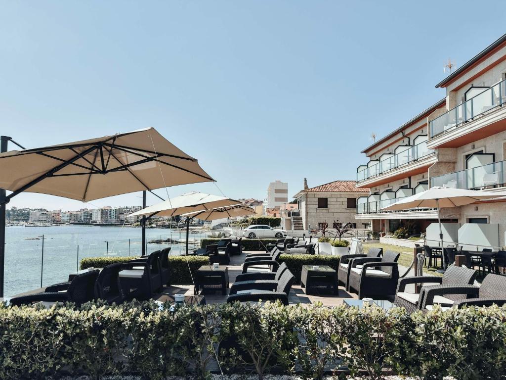 - un groupe de chaises longues et de parasols sur une plage dans l'établissement Hotel Mardevela, à Sanxenxo