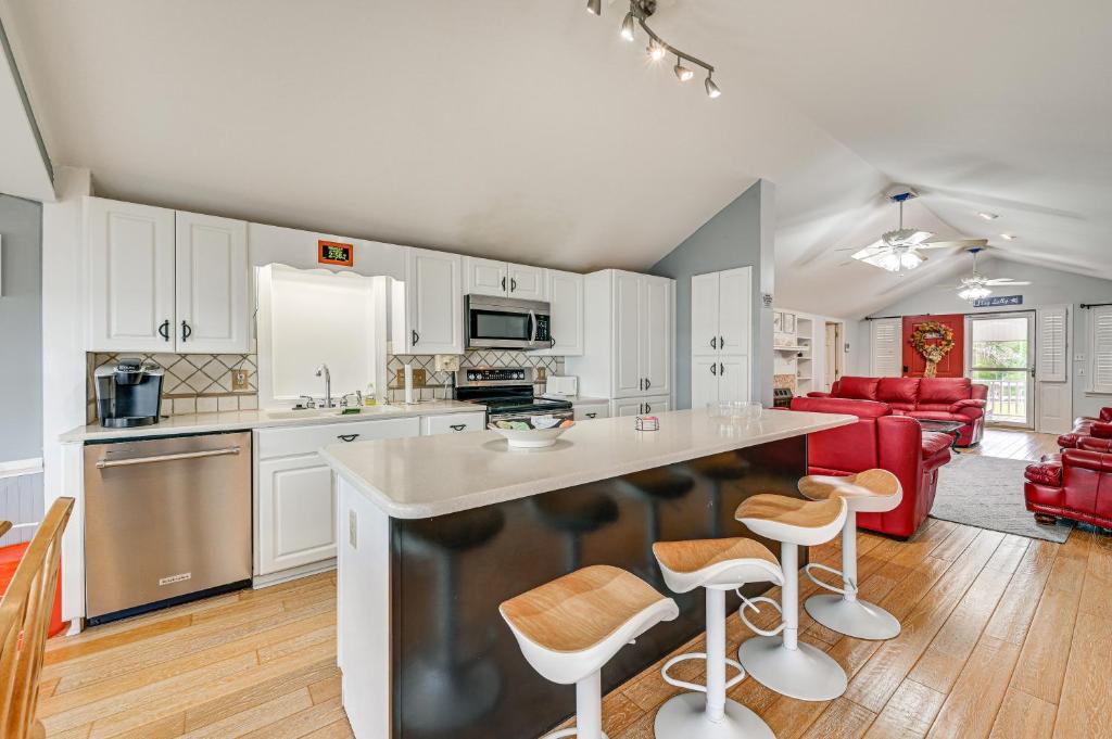 una cocina con armarios blancos y una isla de cocina con taburetes en Pamlico River House with Private Dock and River View!, en Washington