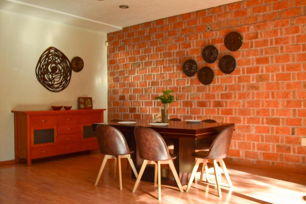une salle à manger avec un mur en briques, une table et des chaises dans l'établissement Valentin House, very spacious and cozy., à San Luis Potosí