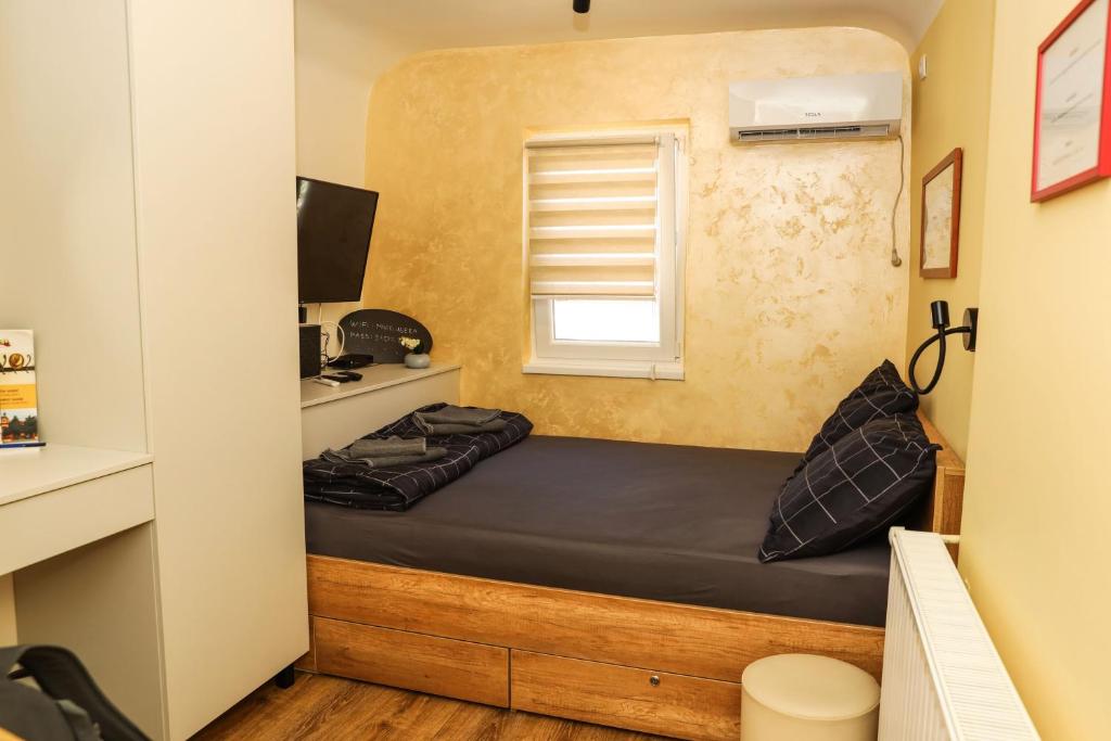 ein kleines Bett in einem kleinen Zimmer mit Fenster in der Unterkunft Business Suite Novi Sad Center in Novi Sad