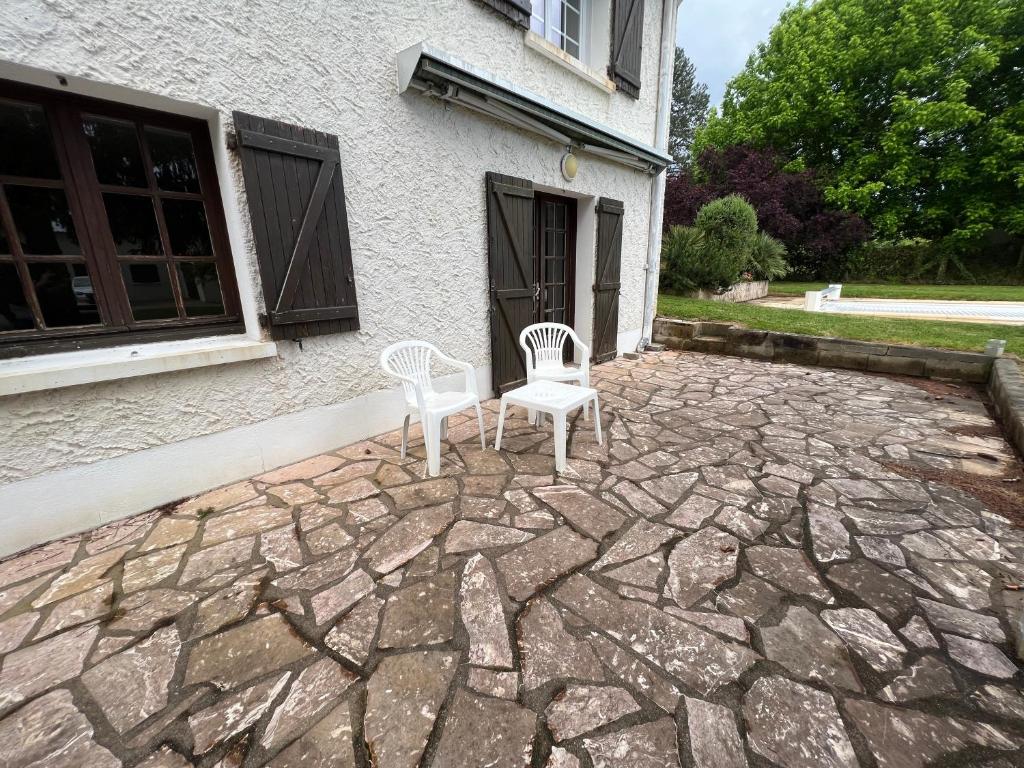 two chairs sitting on a stone patio in front of a house at T1 bis 35m2 chez Laurie et Xavier in Mignaloux-Beauvoir