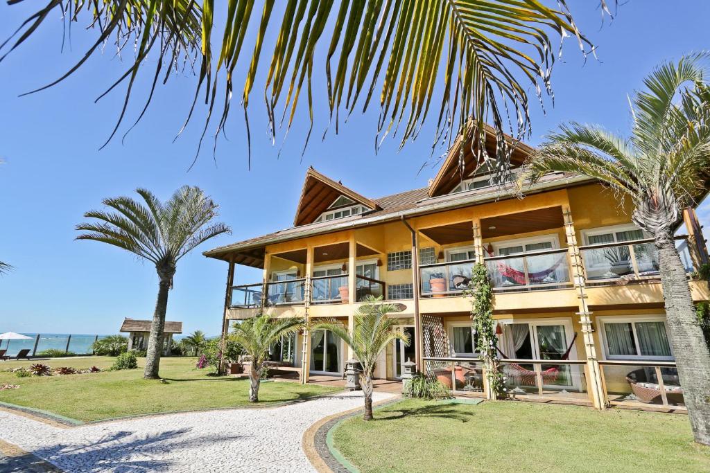Praia do Estaleiro Guest House في باليريو كامبوريو: منزل أمامه أشجار نخيل