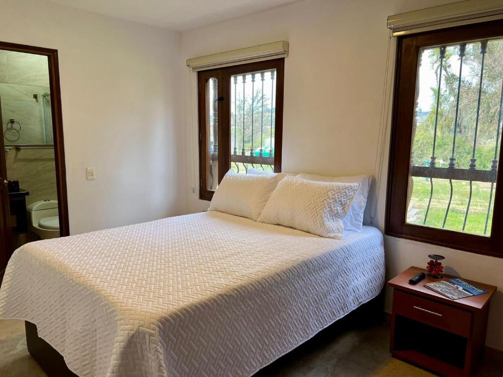 1 dormitorio con 1 cama blanca y 2 ventanas en Casa Akuaina en Villa de Leyva