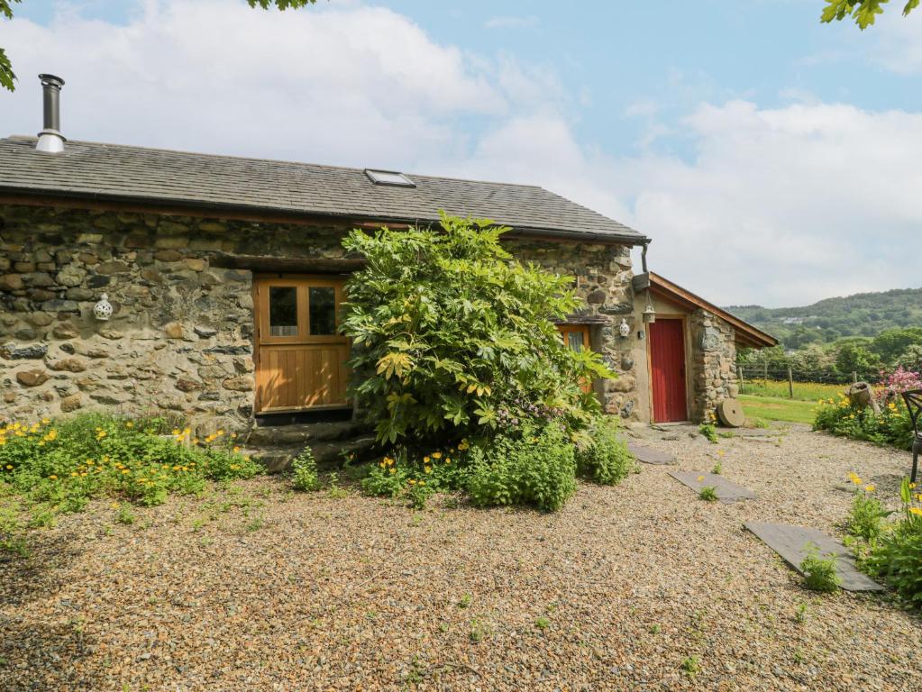 a stone house with a red door and a yard at The Shippon in Conwy