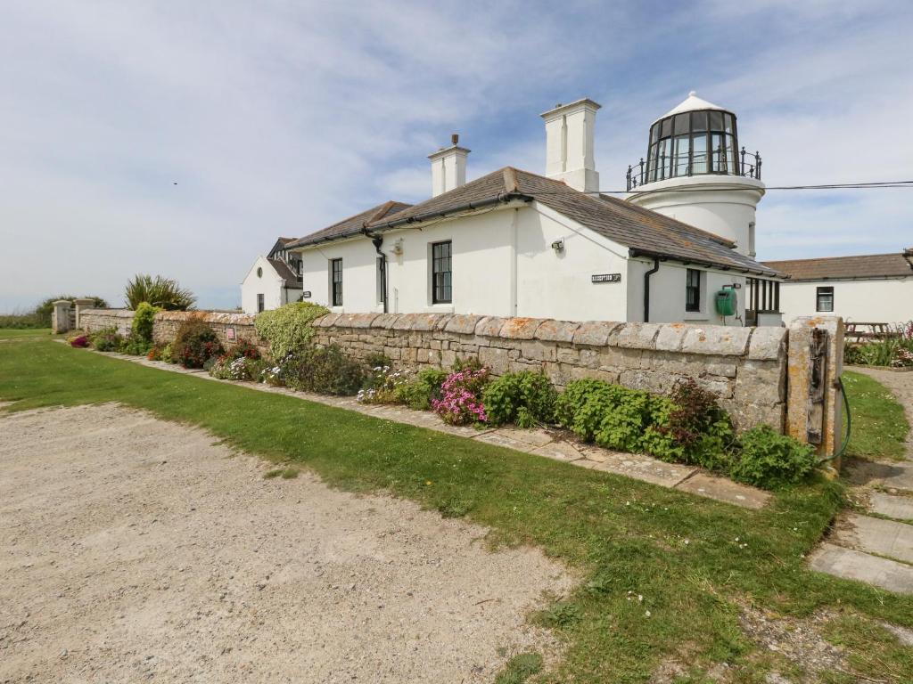 a house with a lighthouse in the background at Old Higher Lighthouse Stopes Cottage in Southwell