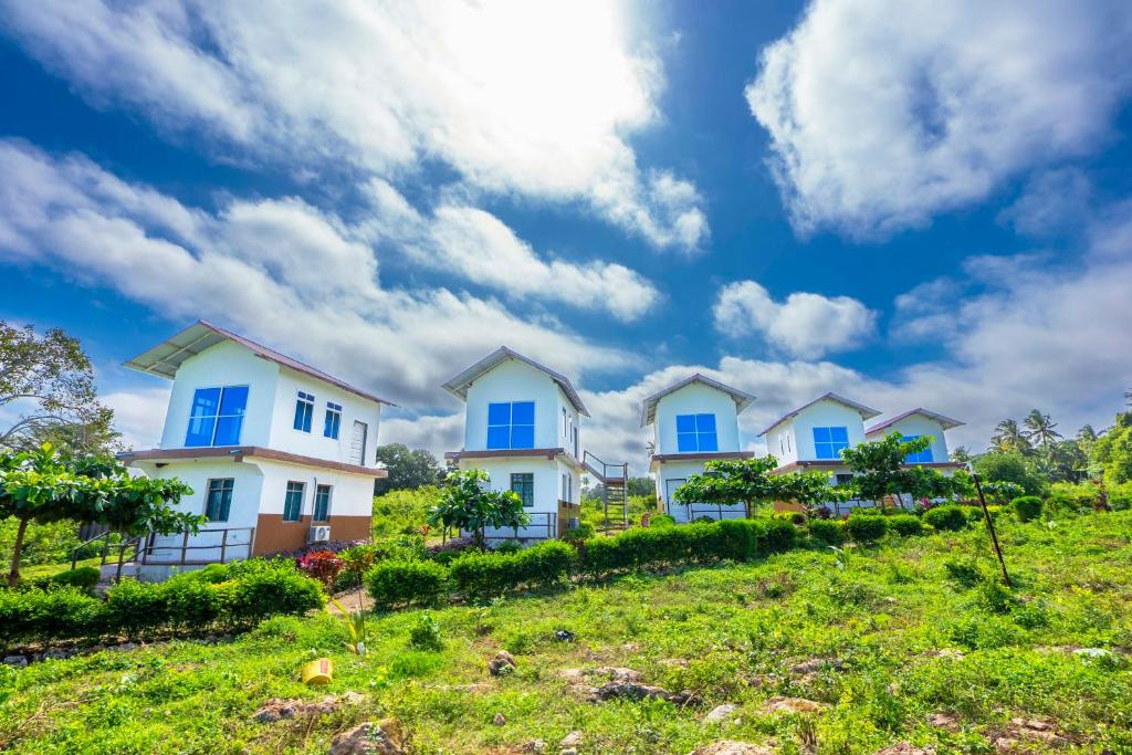 a row of houses with blue windows on a hill at Mangapwani Beach villa in Fujoni