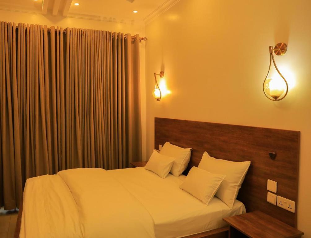 - une chambre dotée d'un grand lit avec des draps et des oreillers blancs dans l'établissement Ally Ngali, à Kigali