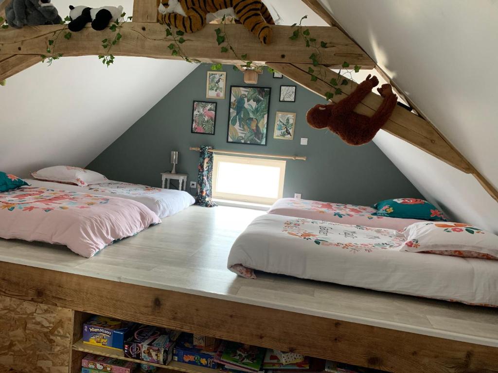 a attic bedroom with two beds and a window at Le Pressoir Macy - Terracobois in Choussy