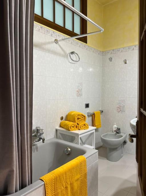 a bathroom with a tub and a toilet and yellow towels at Casa di Fausto - CityLife Apartment in Milan