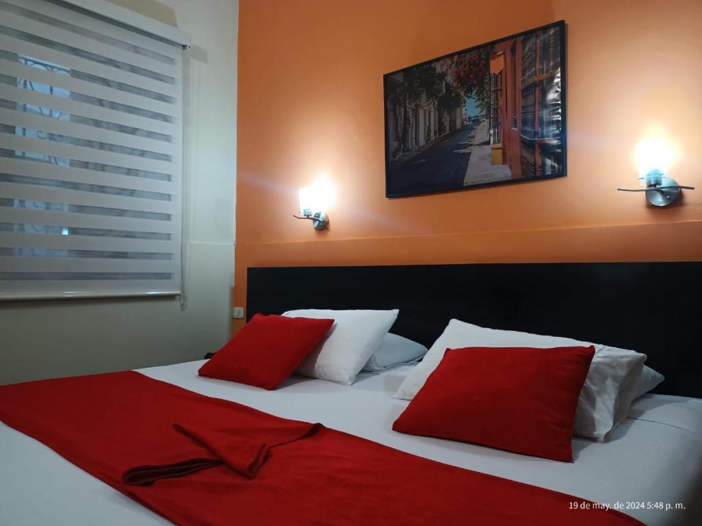 sypialnia z łóżkiem z białymi i czerwonymi poduszkami w obiekcie Hotel La Herreria Colonial w mieście Popayán
