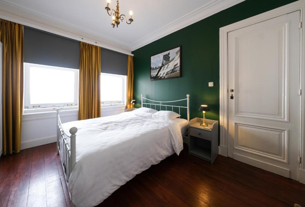 a bedroom with a white bed and green walls at Your homestay in a bibliophile mansion in Antwerp