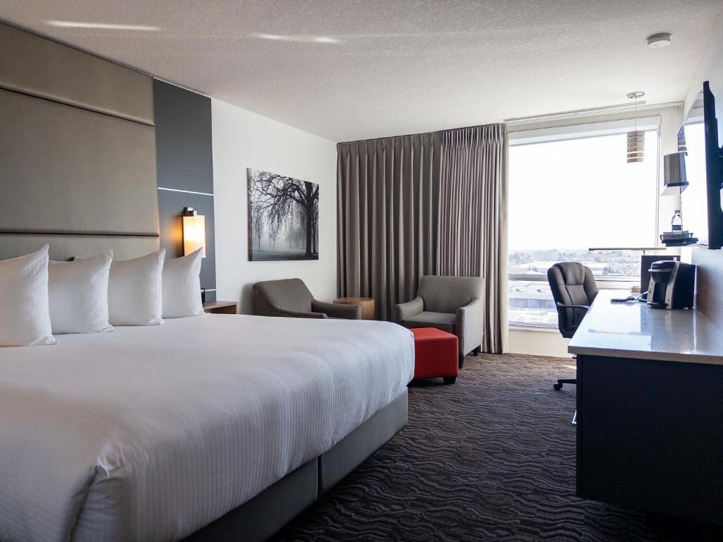 Una habitación de hotel con una cama grande y una ventana. en Carriage House Hotel and Conference Centre, en Calgary