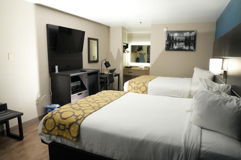 Baymont Inn & Suites في مانينغ: غرفة فندقية بسريرين وتلفزيون بشاشة مسطحة