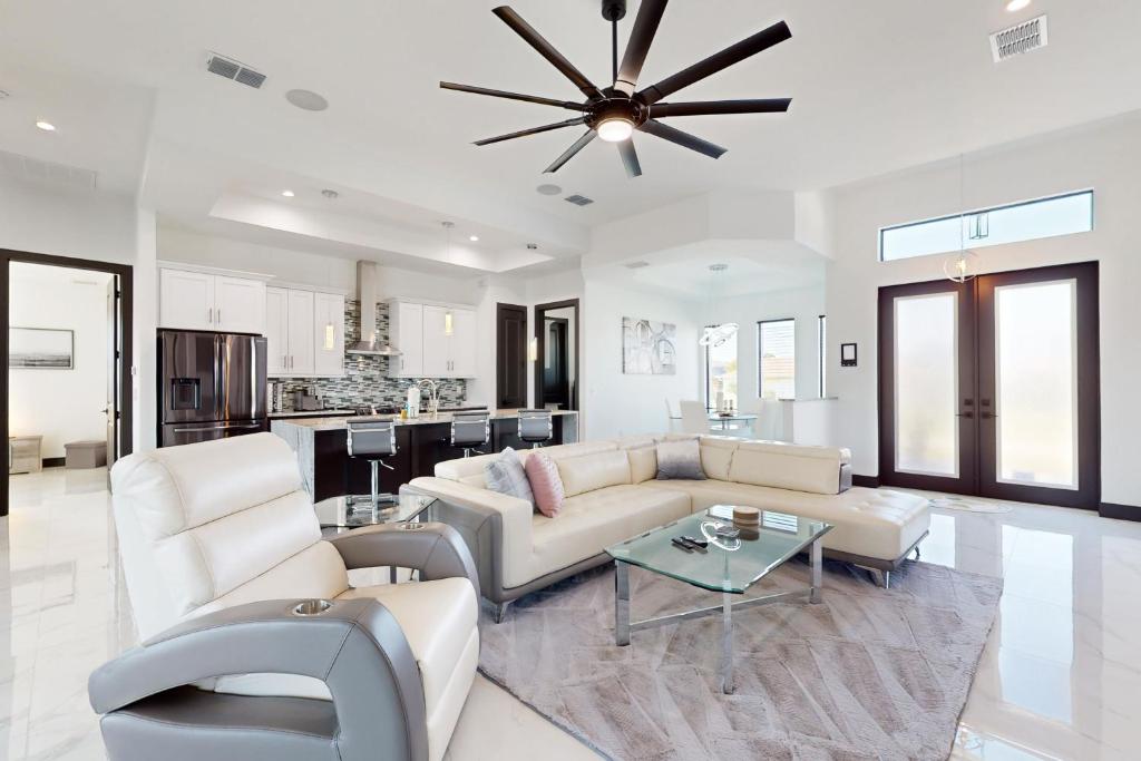 ein Wohnzimmer mit weißen Möbeln und einem Deckenventilator in der Unterkunft Sunset Serenity in Cape Coral
