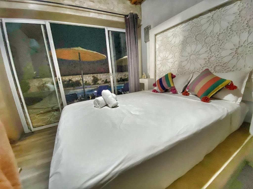 Villa Charfa Élégance Confort et Vues Panoramiques في الصويرة: غرفة نوم مع سرير أبيض كبير مع نافذة