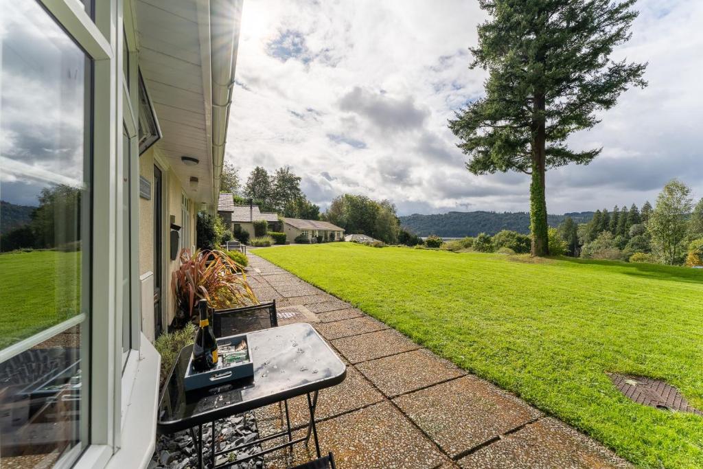 een patio met een tafel en uitzicht op een veld bij Lowera Cottage in Windermere