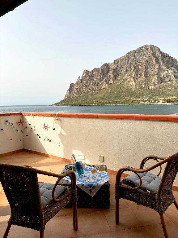 un tavolo e delle sedie su un balcone con una montagna di Residenza sul Mare Baia Cornino a Custonaci