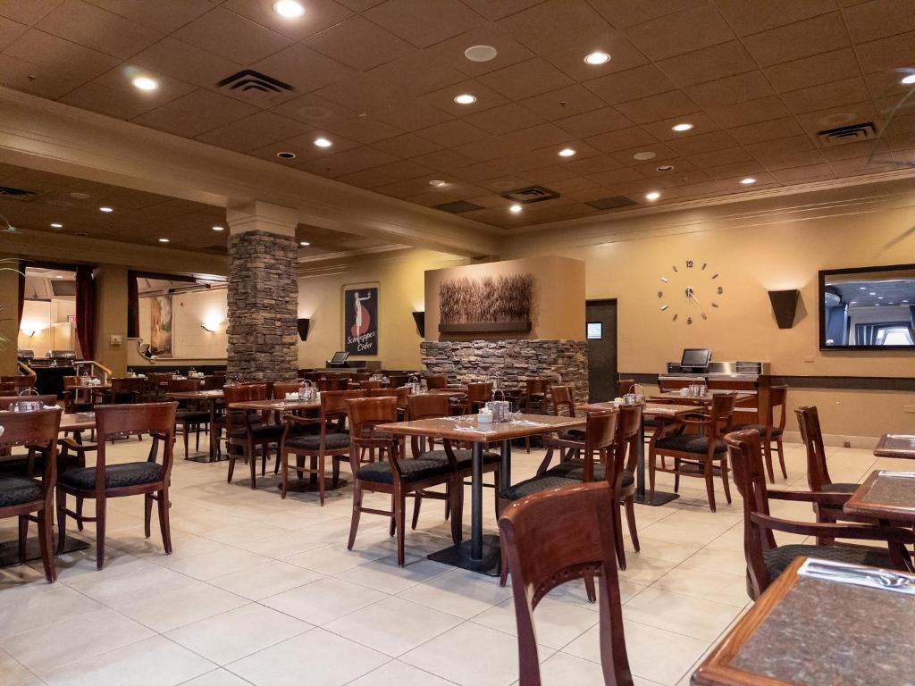 un restaurante con mesas y sillas de madera y TV en Carriage House Hotel and Conference Centre, en Calgary