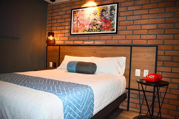 a bedroom with a bed and a brick wall at Hotel Marti in Mexico City