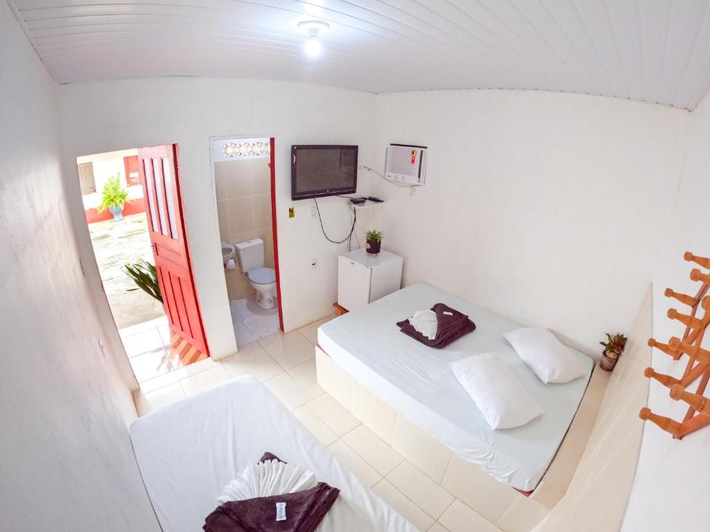 a small white room with a bed and a tv at Pousada Paraíso in Novo Airão
