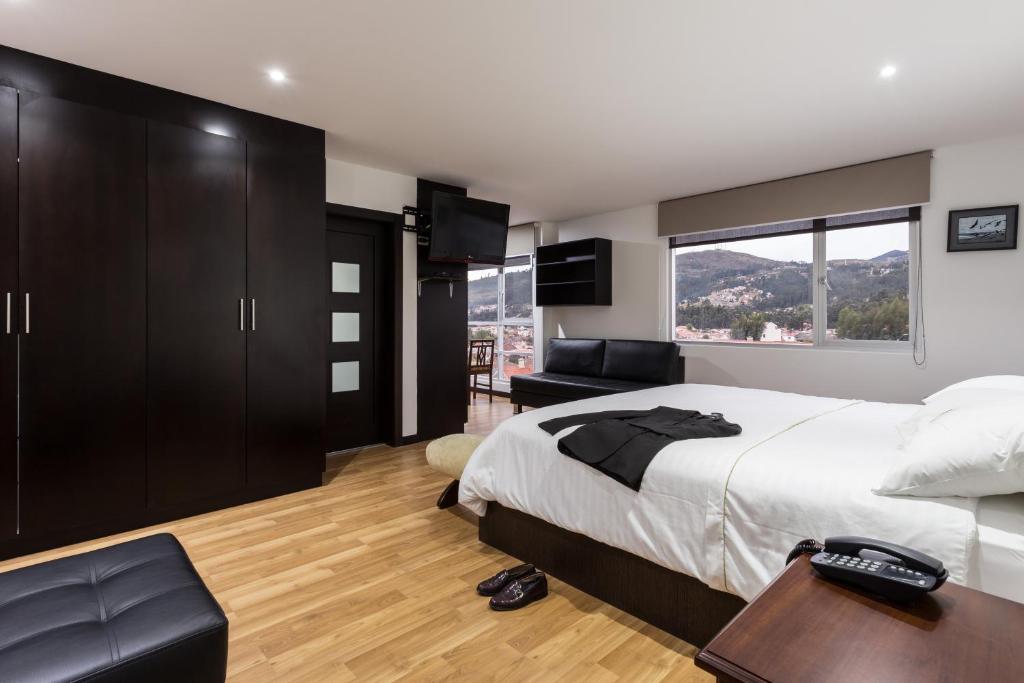 a bedroom with a bed and a desk and a window at Gaviota Apartments & Suites in Cuenca