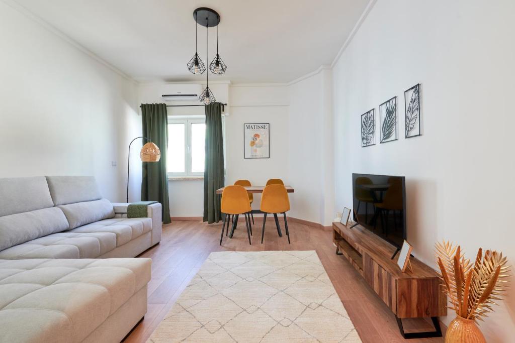 a living room with a couch and a tv at Sunny - Cozy Apartment in Amadora