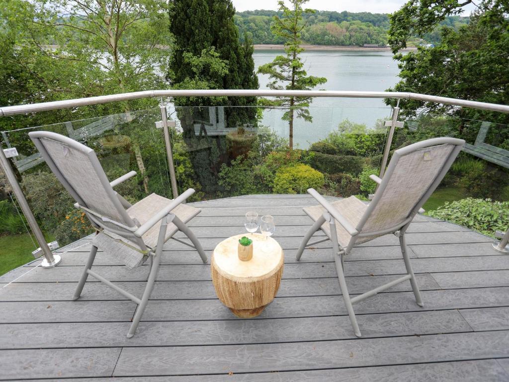 two chairs and a table on a deck with a view of the water at Ynys Castell in Menai Bridge