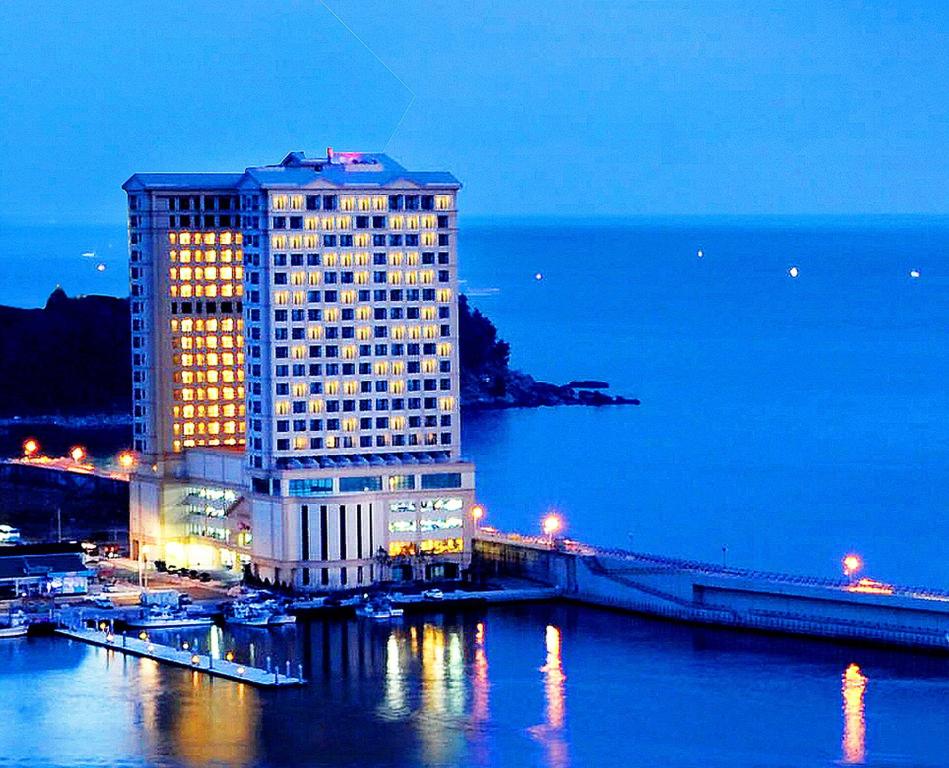 a tall building with lights on in front of the water at Ramada by Wyndham Gangwon Sokcho in Sokcho