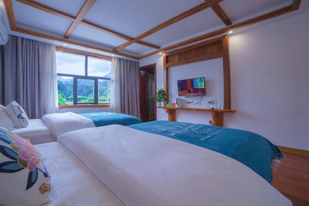 a bedroom with two beds and a window at Easy House in Zhangjiajie