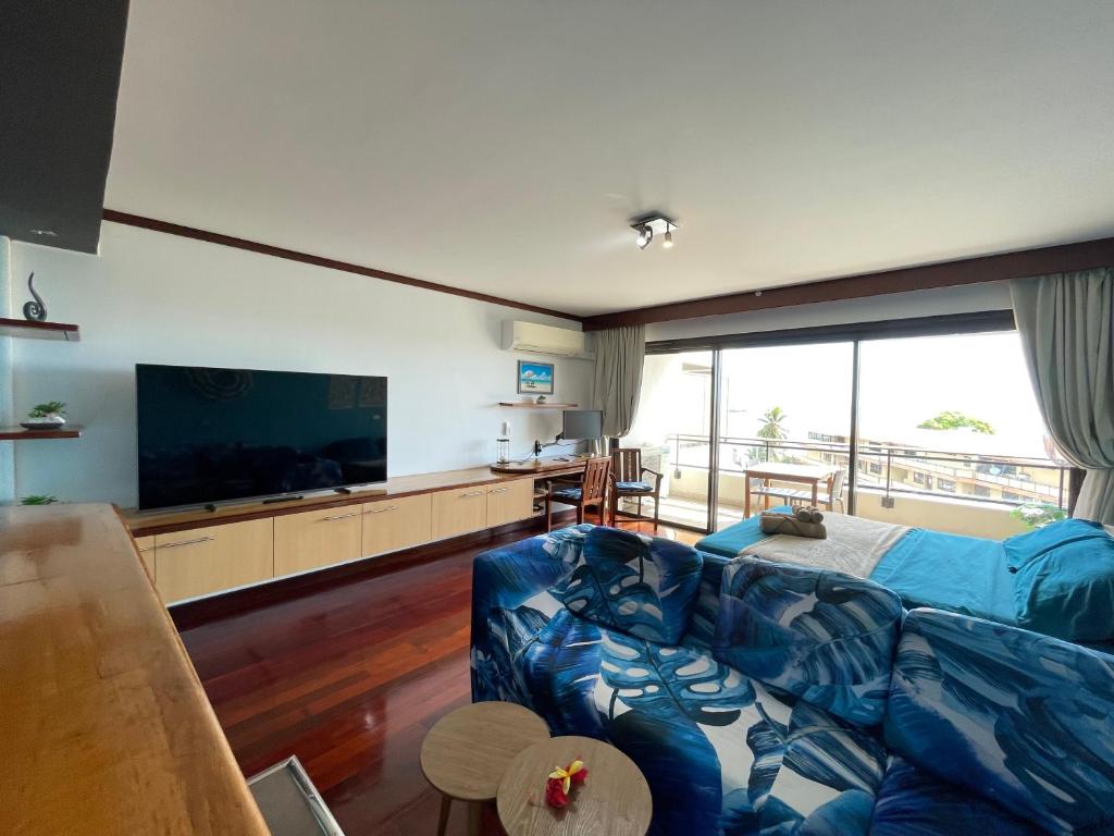un soggiorno con divano blu e TV a schermo piatto di Studio Blue Moana - Private apartment with sea view a Papeete
