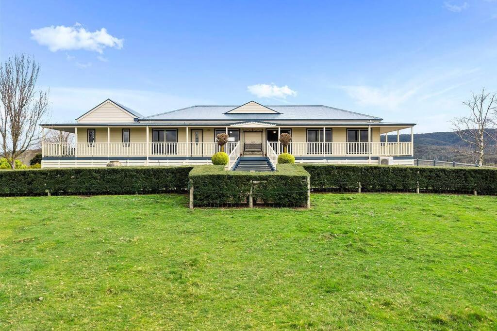 una gran casa blanca con césped delante en IRONBARK FARM Farmhouse on 52 acres in the scenic Yarra Valley, en Glenburn