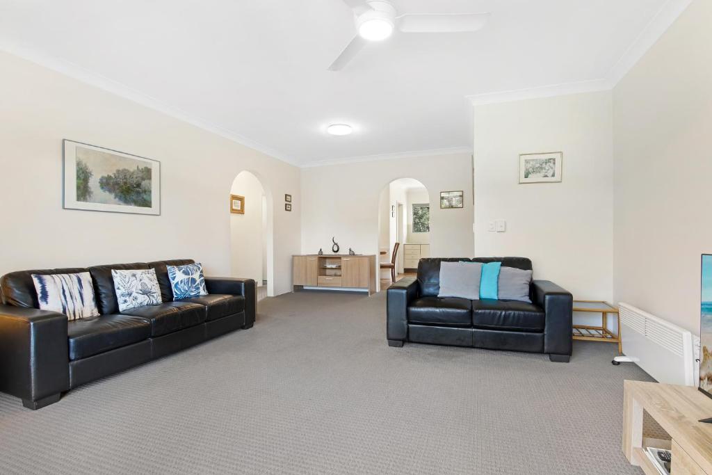 a living room with two black couches and a table at Hawaiian Gardens 22 in Coffs Harbour