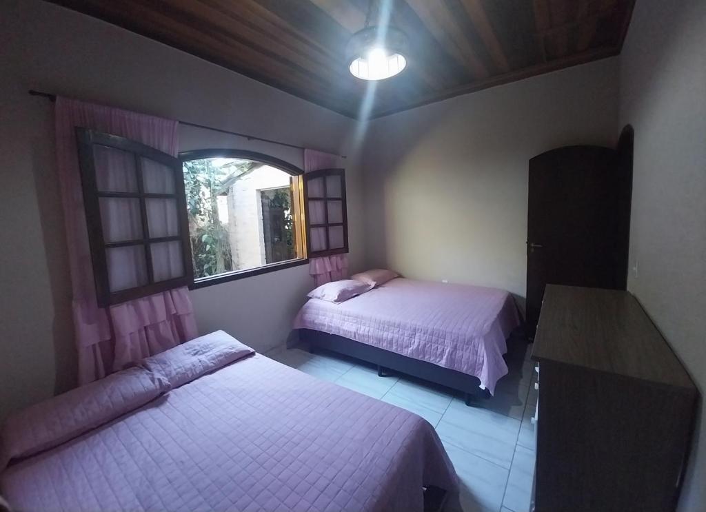 ラゴイーニャにあるAconchegante Sítio em Lagoinha SPのベッド2台と窓のある寝室